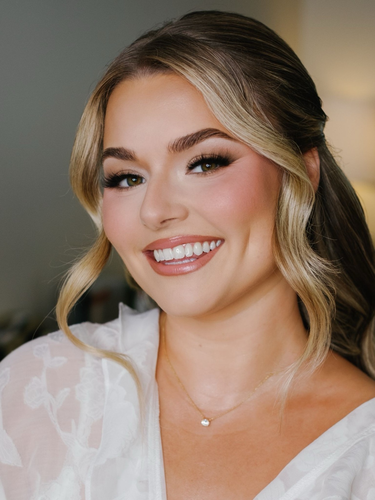A smiling bride with soft waves and glowing bridal makeup